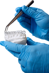 Image of a person with a friendly smile, showing their teeth and mouth, with two hands holding their palms together, indicating a friendly gesture, with a message about prosthodonti care